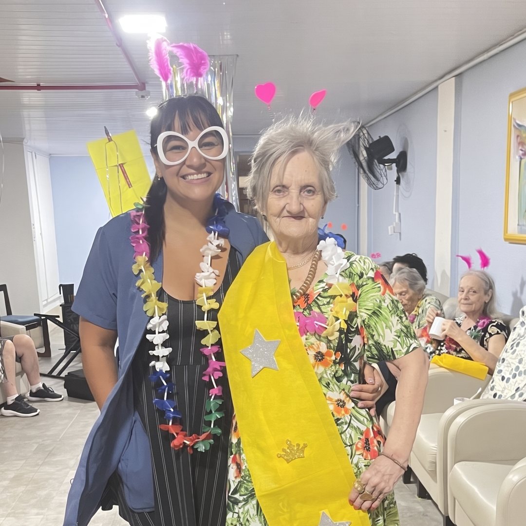 Cuidadora abraçada a uma senhora numa festa